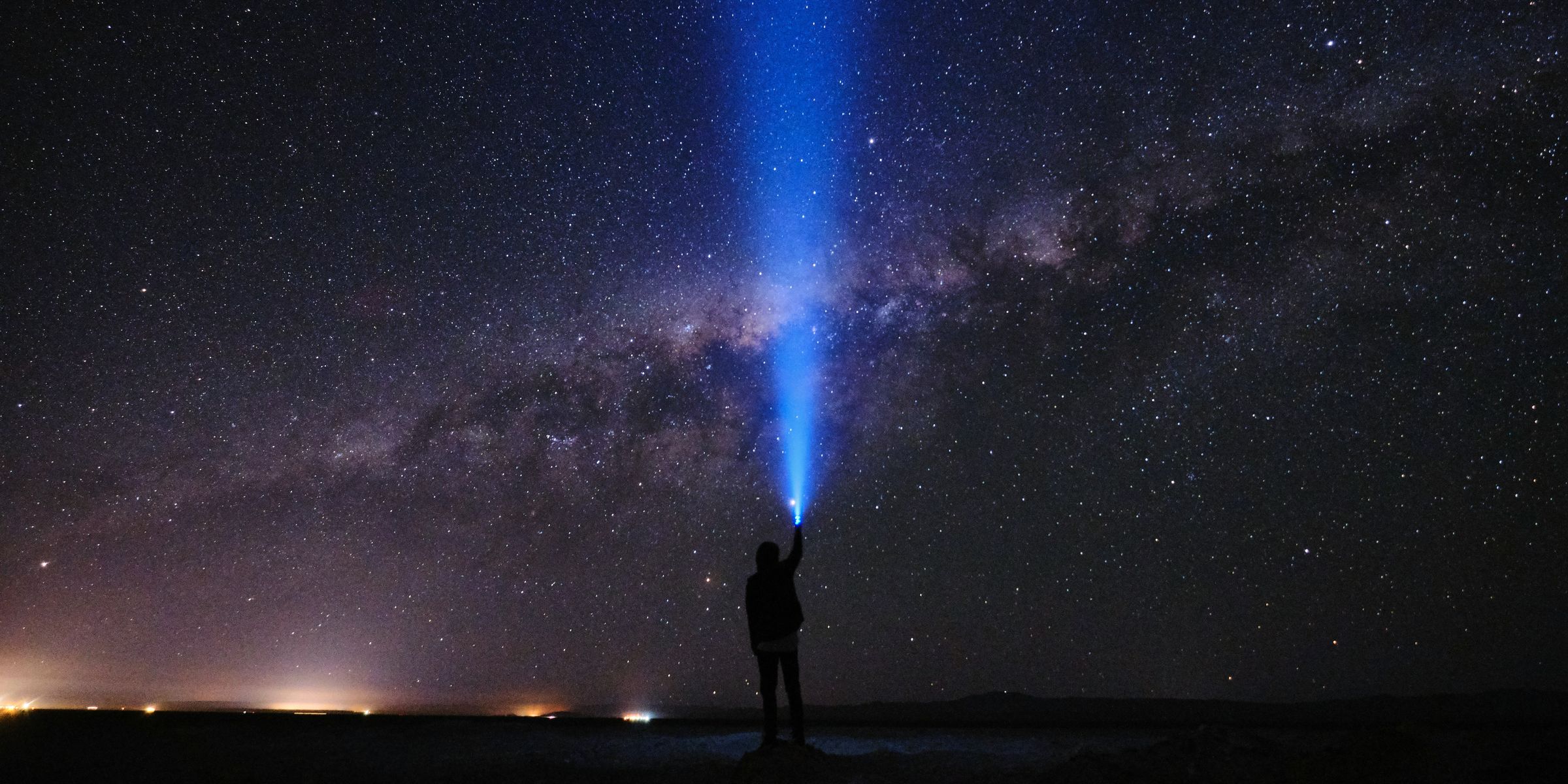 Pessoa apontando uma lanterna para a Via Láctea no céu do Atacama