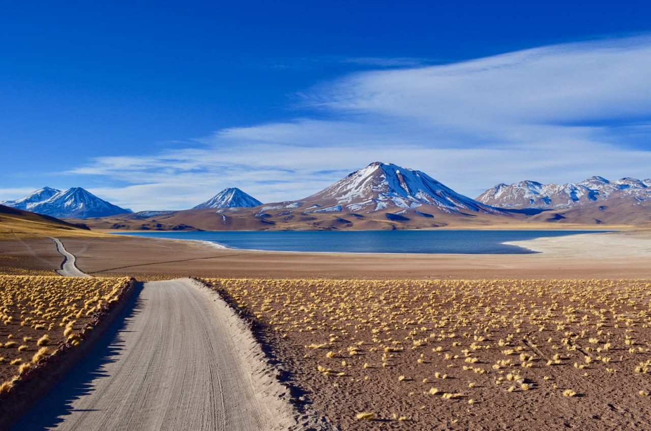 Estrada de terra rumo às Lagunas Altiplânicas, vulcões ao fundo